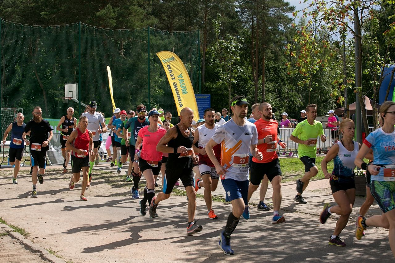 Grupa biegaczy, kobiet i mężczyzn, tuż po wystartowaniu biegu. 